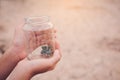 Hands of girl holding little plant in glass jar on cracked dry background Royalty Free Stock Photo