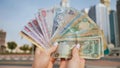 Hands of a girl holding money of the United Arab Emirates on the background of Dubai skyscrapers. Royalty Free Stock Photo