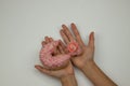 Hands of a girl holding a pink bitten donut, discount sale goods Royalty Free Stock Photo