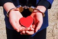 The hands of a girl holding hands in the shape of a red heart together with handcuffs Royalty Free Stock Photo