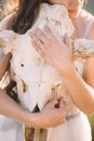 Hands of a girl hugging a white deer skull, close-up