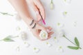 Hands girl master eyelash extension on white flowers background with pink brush, top view. Beauty concept