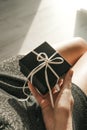 The hands of a girl in a silver dress holds a gift with a white ribbon in the red carpet. gift for new year, birthday, valentine`s Royalty Free Stock Photo