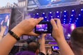 Kemerovo, Russia, 07.27.2019: Hands of a girl who photographs the performance of a rock band at a free music festival in honor of