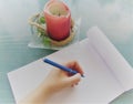 Hands of girl writing with a blue pen in notebook and Desert candle standing on green Table wooden background. Royalty Free Stock Photo