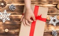 Hands giving or receiving a gift in craft paper with a red ribbon on wood Christmas and New Year background. Top view Royalty Free Stock Photo