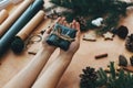 Hands giving rustic christmas gift in black wrapping paper with cinnamon decoration, and pine branches, cones, gingerbread cookies Royalty Free Stock Photo