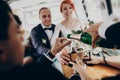 Hands with glasses of champagne, stylish happy bride and groom toasting laughing and having fun with bridesmaids and groomsmen