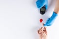 Hands of gloved doctor with glucometer taking blood sugar reading from caucasian woman, copy space