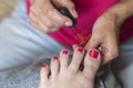 Hands in gloves cares about a woman's foot nails. Pedicure, manicure beauty salon concept. Nail varnishing in red color.