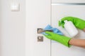 Hands in gloves cleaning door handle with rag and spray detergent, closeup Royalty Free Stock Photo