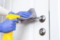 Hands in gloves disinfecting door handle with rag and spray detergent Royalty Free Stock Photo