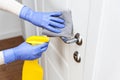 Hands in gloves disinfecting door handle with rag and spray detergent Royalty Free Stock Photo