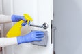 Hands in gloves disinfecting door handle with rag and spray detergent Royalty Free Stock Photo