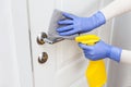 Hands in gloves disinfecting door handle with rag and spray detergent Royalty Free Stock Photo