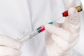 Hands in gloves filling medicine from ampule into syringe against the background of medical robe