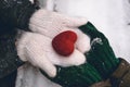 Hands in gloves holding heart closeup on winter snow background. Toned. Royalty Free Stock Photo