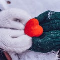 Hands in gloves holding heart closeup on winter snow background. Toned.