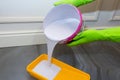 Hands are in gloves, pour a paint from a bucket in a yellow container Royalty Free Stock Photo