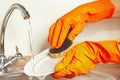 Hands in gloves wash the dirty dishes under running water in kitchen Royalty Free Stock Photo