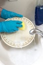 Hands in gloves wash a plate under running water Royalty Free Stock Photo