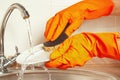 Hands in gloves wash the plate under running water in kitchen Royalty Free Stock Photo