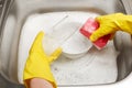 Hands in gloves washing glass with pink cleaning sponge Royalty Free Stock Photo