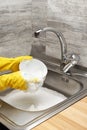 Hands in gloves washing white bowl with blue cleaning sponge Royalty Free Stock Photo