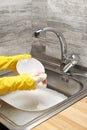Hands in gloves washing white bowl with pink cleaning sponge Royalty Free Stock Photo