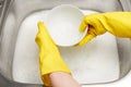 Hands in gloves washing white bowl under running tap water Royalty Free Stock Photo