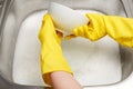 Hands in gloves washing white bowl under running tap water Royalty Free Stock Photo