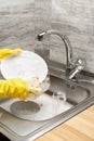 Hands in gloves washing white plate with pink cleaning sponge Royalty Free Stock Photo