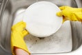 Hands in gloves washing white plate under running tap water Royalty Free Stock Photo