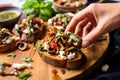 hands grabbing a slice of mushroom bruschetta from a platter