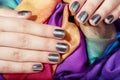 Hands with gray manicured nails on colorful textile background Royalty Free Stock Photo