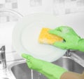 Hands in green gloves wash white plate Royalty Free Stock Photo