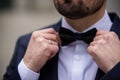 the hands of the groom bow tie. stylish groomsmen helping happy groom getting ready in the morning for wedding ceremony. luxury