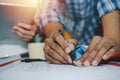 Hands of group engineer and architect working on blueprint and mobile tablet on workplace desk