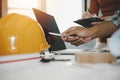 Hands of group engineer and architect working on laptop computer and blueprint on workplace desk