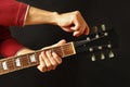 Hands of guitarist tunes the guitar on dark background