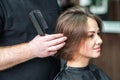 Hairdresser`s hand checking hair of woman