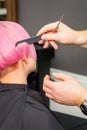 Hands of hairdresser combing hair making short pink hairstyle for a young caucasian woman in a beauty salon. Royalty Free Stock Photo