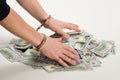 Hands handcuffed over a bunch of dollars, over white background Royalty Free Stock Photo