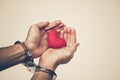 Hands with handcuffs holding a red heart