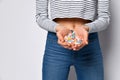 Hands with a handful of a variety of multi-colored drugs pills tablets on the background of female legs