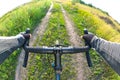 hands on the handlebars of a bicycle of a cyclist riding along a trail in nature. Point of view Royalty Free Stock Photo