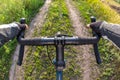 hands on the handlebars of a bicycle of a cyclist riding along a trail in nature. Point of view Royalty Free Stock Photo