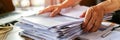 Hands handling a substantial pile of documents in an office setting. Concept of corporate documentation and office work Royalty Free Stock Photo