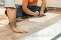 Hands of handyman beat the laminate plank to laying the laminate floor