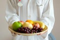 The hands of a healthy nutritionists, she holds a bowl with fruits, apples, grapes and avocados